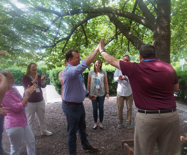 Group photo, two men in the center, high-fiving