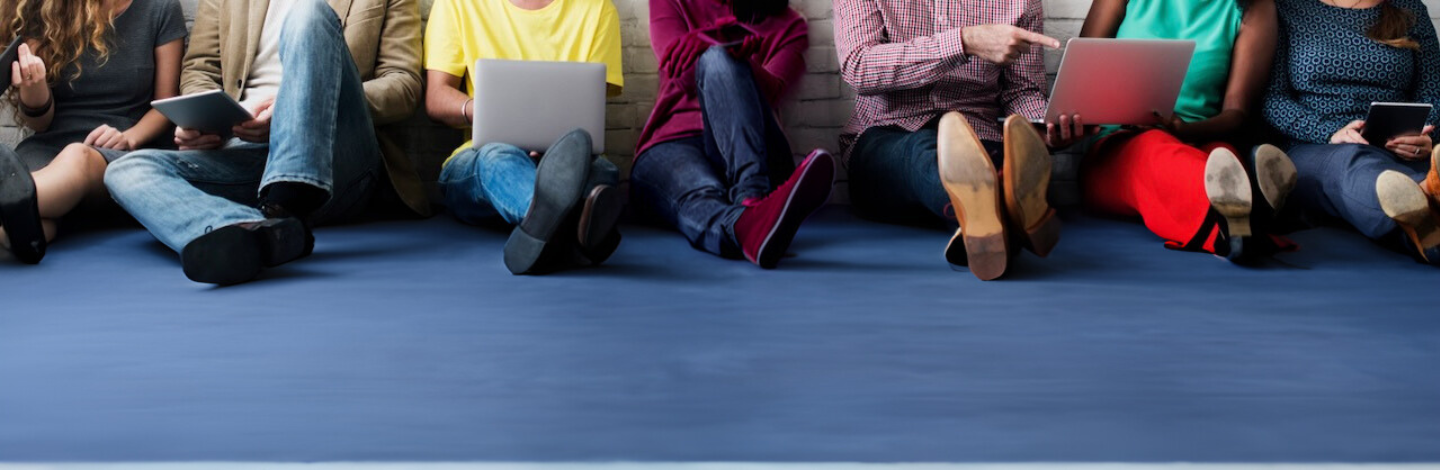 Group of high school students sitting on the floor, lined up against the wall, working together